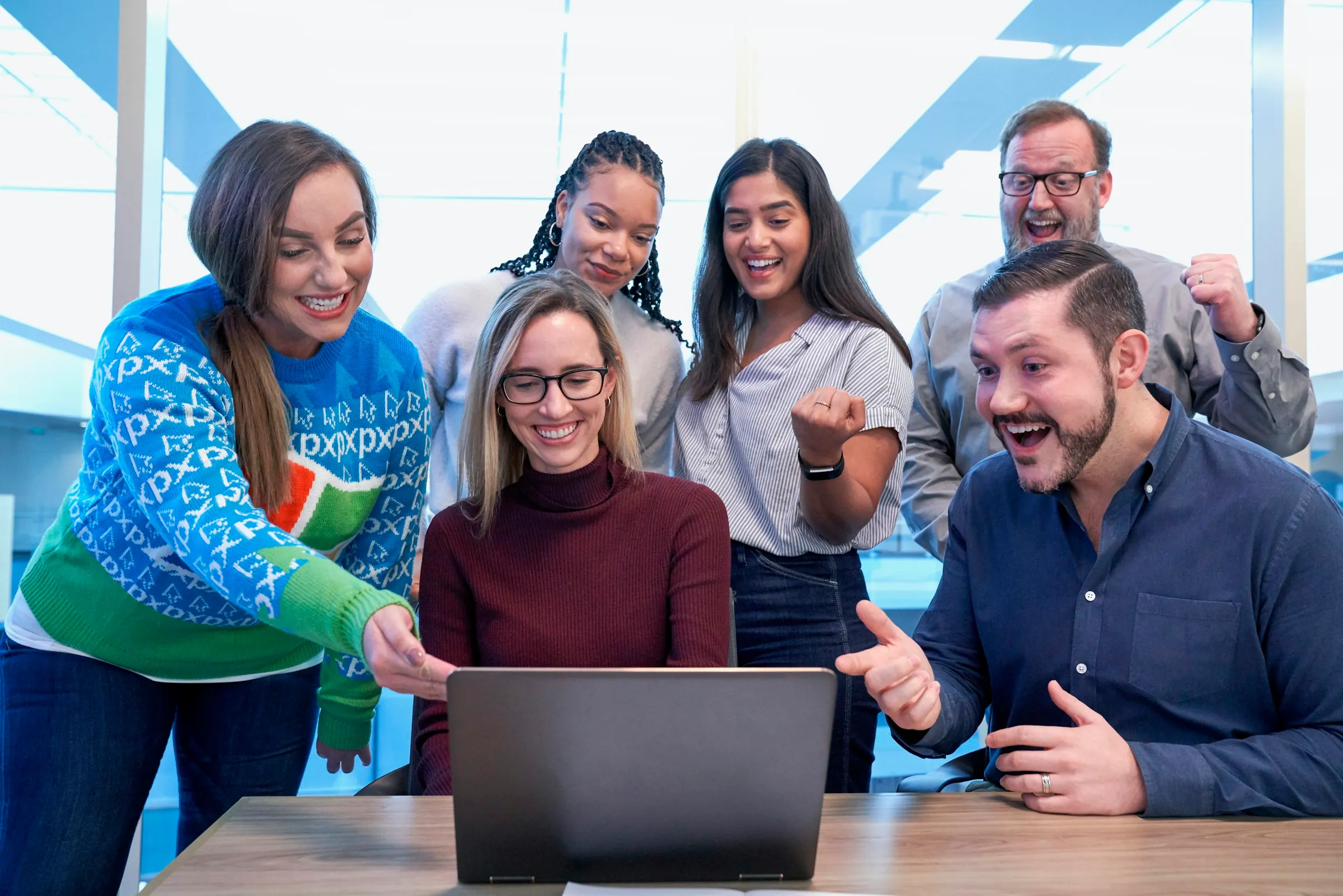 Cheerful team gathered around a laptop